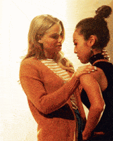 two women standing next to each other with one wearing a striped shirt