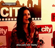 a woman is singing into a microphone in front of a sign that says city .