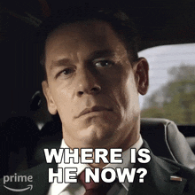 a man in a suit and tie is sitting in a car and asking where is he now
