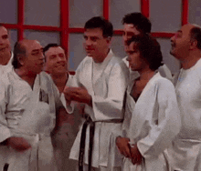 a group of men in karate uniforms are standing next to each other in a room .