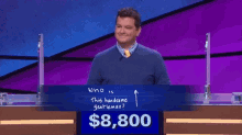 a man stands in front of a blue board that says who is this handsome gentleman on it
