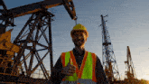 a man wearing a hard hat and safety vest is giving a thumbs up sign
