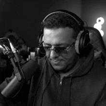 a man wearing headphones and sunglasses looks down at something