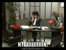 a woman sits at a desk talking on a phone with ntpiiiiiiiiiiin written on the bottom