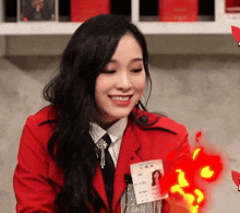 a woman in a red jacket is smiling and holding a id card with her name on it