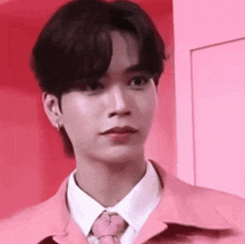 a young man is wearing a pink jacket and tie .