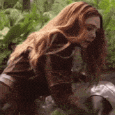 a woman with long red hair is kneeling down in the dirt .