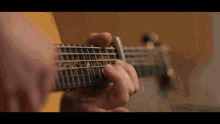 a person is playing an acoustic guitar with a yellow background