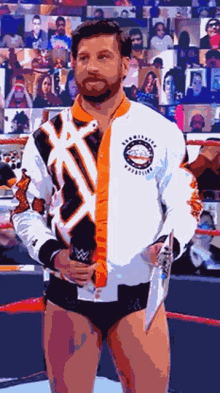 a man in a wrestling ring holding a microphone and wearing a jacket that says ' wrestling ' on it