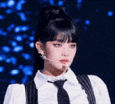a woman wearing a white shirt and a black tie with a microphone in her mouth