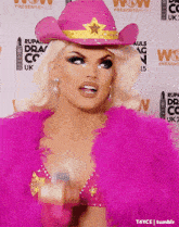 a woman wearing a pink cowboy hat and a pink feather coat
