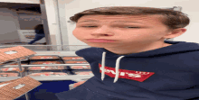 a boy wearing a blue levi 's sweatshirt stands in front of a display case of meat