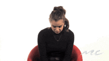 a woman in a black turtleneck sits in a chair