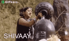 a woman in a black dress is pouring water from a large pot .