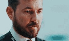a man with a beard wears a police lanyard around his neck