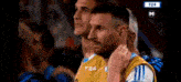 a group of soccer players are watching a game on a television screen .