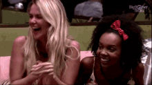 two women are laughing together while sitting on a couch .