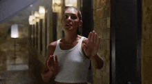 a woman in a white tank top is walking down a hallway .