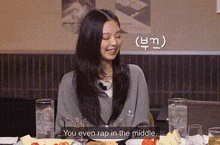a woman is sitting at a table with a plate of food and drinks and talking to someone .