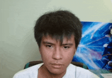 a close up of a young man 's face in front of a painting on the wall