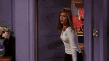 a woman in a white shirt is standing in front of a purple door with a poster that says xcl on it