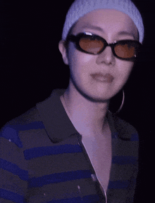 a woman wearing sunglasses and a striped shirt looks at the camera