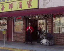 a man in a red jacket stands in front of a store with an open sign