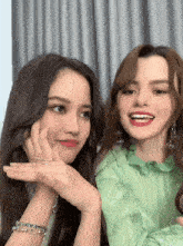 two women are sitting next to each other and one is wearing a green dress