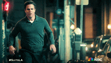 a man is running down a street with a nbc logo on the bottom