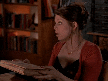 a woman sitting at a table with a book and the words knock yourself out behind her
