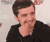 a man is smiling with his hand on his chin in front of a sign that says bsw