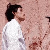 a man in a white shirt and tie is standing in front of a wall covered in blood .