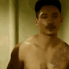 a shirtless man with a tattoo on his chest is looking at the camera