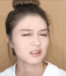 a woman with a bun on her head is making a funny face with her eyes closed .