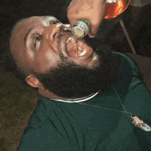 a man with a beard is drinking from a bottle with his tongue out