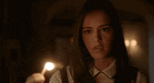 a woman holds a lit match in her hand in the dark