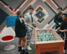 a group of people standing around a foosball table with rtve written on the bottom
