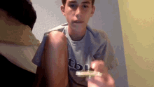 a boy wearing a tbi shirt is holding a card