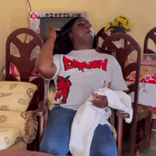 a man is sitting in a chair wearing a shirt that says dash
