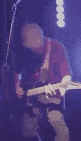 a man is playing an electric guitar on a stage in front of a microphone .
