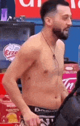 a shirtless man with a beard and headphones is standing in front of a sign that says panettone .