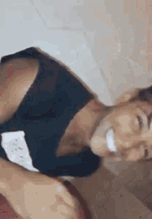 a man in a black shirt is smiling while laying on a toilet .