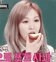 a girl with pink hair is eating an apple while wearing a school uniform .