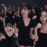 a woman in a black dress stands in a crowd of women
