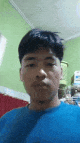 a young man in a blue shirt is taking a selfie in a room .