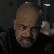 a bald man with a beard and mustache is looking at the camera in a dark room .