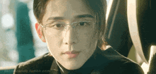 a man wearing glasses and a black turtleneck is looking at the camera
