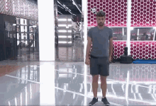 a man in a grey shirt and shorts is standing in front of a red wall