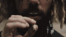 a man with dreadlocks and a nose ring is smoking a marijuana joint .
