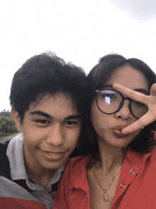 a boy and a girl are posing for a picture and the girl is wearing a red shirt